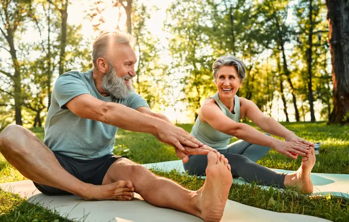Older couple stretching outdoors in the park.