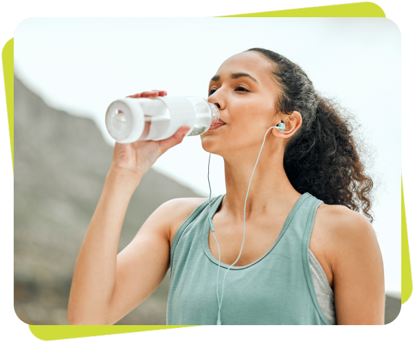 k1 A woman drinking water from a bottle while wearing headphones.